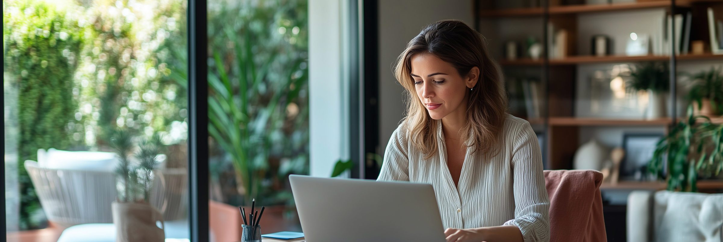 A small business owner working on her laptop in a bright home office